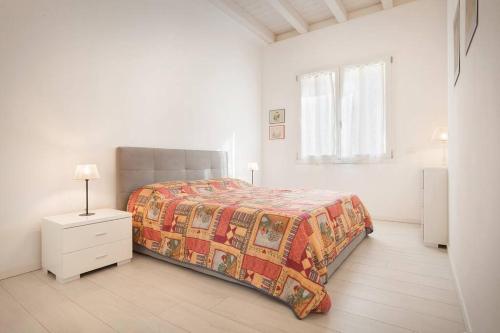 a white bedroom with a bed and a dresser and a window at Villa Malù - APT Luisa Piscina e vista lago in Torri del Benaco