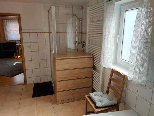 a bathroom with a shower and a chair and a window at zentrale & ruhige Ferienwohnung in Mössingen