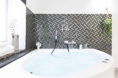 y baño con bañera blanca y pared de azulejos. en Trastevere Silver King JacuzziSuite -TopCollection, en Roma