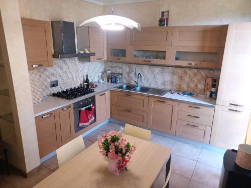 a kitchen with wooden cabinets and a table with flowers on it at CASAVACANZE MEVANIA in Bevagna