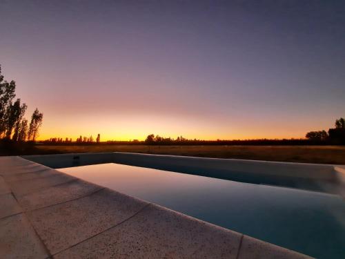 een overloopzwembad met een zonsondergang op de achtergrond bij Finca Los Racimos - Casa Syrah in San Rafael