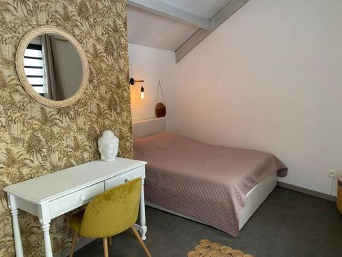 een slaapkamer met een bed, een spiegel en een bureau bij L’aire sans soucis in Le Bois de Nèfles