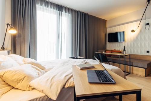 a hotel room with a bed with a laptop on a table at harry's home Bischofshofen hotel & apartments in Bischofshofen