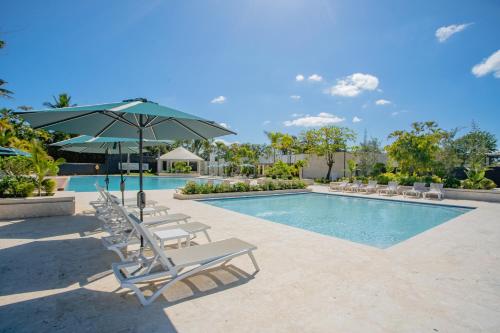 a swimming pool with lounge chairs and an umbrella at Xeliter Green One Playa Dorada in San Felipe de Puerto Plata
