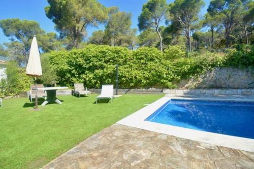 a backyard with a pool and a table and a umbrella at Villa en Platja de Aro with pool 450m from the beach in Platja  d'Aro