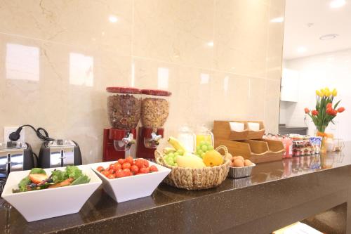a counter with bowls of fruits and vegetables on it at Hotel Prima Busan in Busan