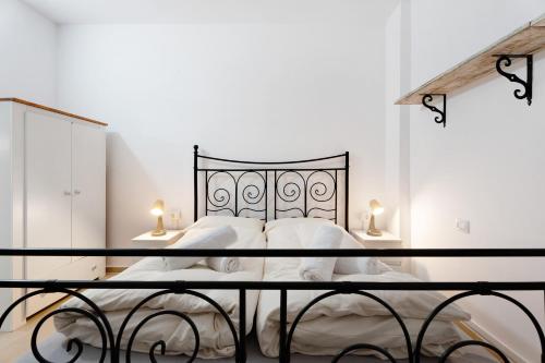 a white bedroom with a black bed with two lamps at Casa Ecuador in Güimar