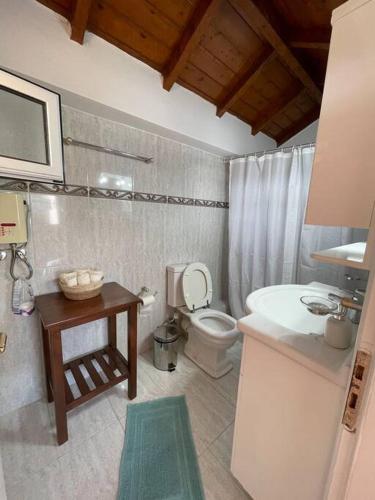 a bathroom with a toilet and a sink and a table at BlackMountain Room in Gythio