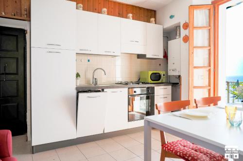 a kitchen with white cabinets and a table at MARINA BAY by Design Studio in Bellano