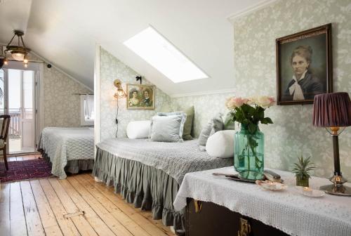 a bedroom with two beds and a vase of flowers on a table at Strandflickornas Havshotell Lysekil in Lysekil