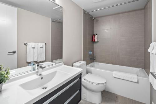 baño blanco con bañera, aseo y lavamanos en Legato Zen Suite by IRIS PROPERTIES!, en Victoria