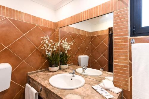 a bathroom with two sinks and a mirror at Pedras D'el Rei in Tavira
