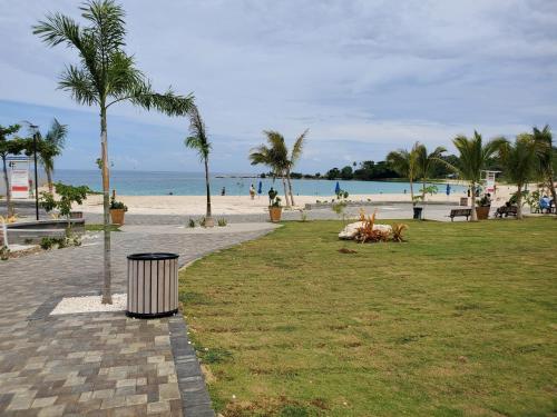 a park next to a beach with palm trees and a trash can at Hillside Retreat in Gated Community Close to Beach in Montego Bay