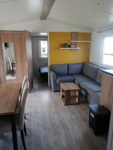 a living room with a couch and a table at MHVACANCES LOUENT PLUSIEURS MOBILHOMES DANS CAMPING 4 ETOILES PROCHE CHATEAUX et ZOO BEAUVAL in Onzain