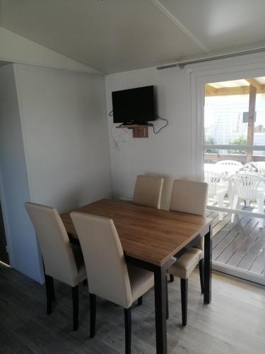 a dining room table with chairs and a television on the wall at MHVACANCES LOUENT PLUSIEURS MOBILHOMES DANS CAMPING 4 ETOILES PROCHE CHATEAUX et ZOO BEAUVAL in Onzain