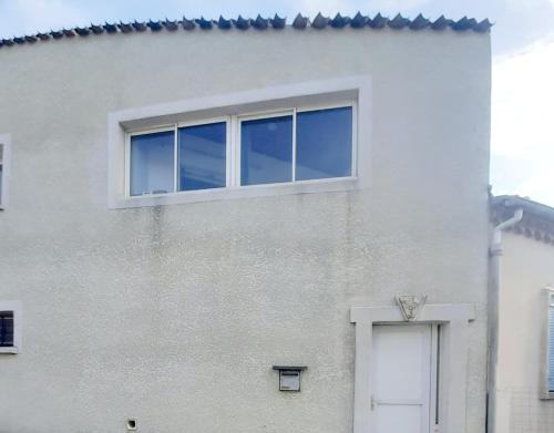 biały budynek z oknem i drzwiami w obiekcie appartement 45m2 parking gratuit en plein centre ville w mieście Valras-Plage