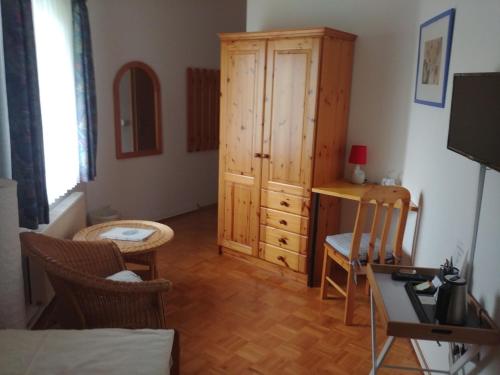 a living room with a wooden cabinet and a desk at Schwarzwald Sportzentrum Neubulach in Neubulach