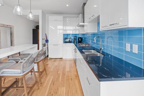 una cocina con armarios blancos y azulejos azules en West Bay Topaz by Iris Properties!, en Victoria