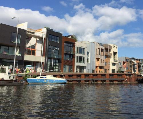 a blue boat in the water next to some buildings at BB in Amsterdam, 35m2, gratis parkeren in Amsterdam