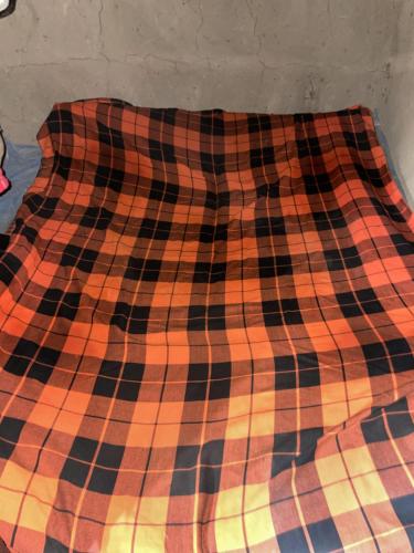 un primer plano de una manta en una cama en DUPOTO HOMESTAY VILLAGE - MASAI VILLAGE (BOMA) en Mto wa Mbu