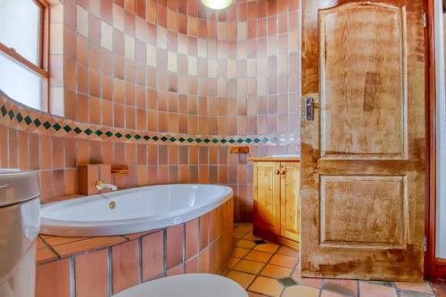 uma casa de banho com uma banheira, um WC e uma porta em Charming Country Villa Sandton with Back Up Power & Water em Joanesburgo