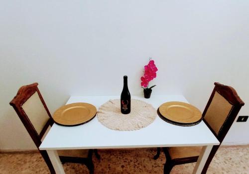 a white table with a bottle of wine and two chairs at CASA VACANZA NONNA EMMA in Lizzano
