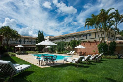 a pool with chairs and a table and a building at Don Quixote Pousada in Tiradentes