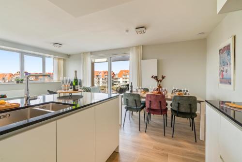 a kitchen and dining room with a table and chairs at Orion View - brand new apartment with swimming pool in Nieuwpoort