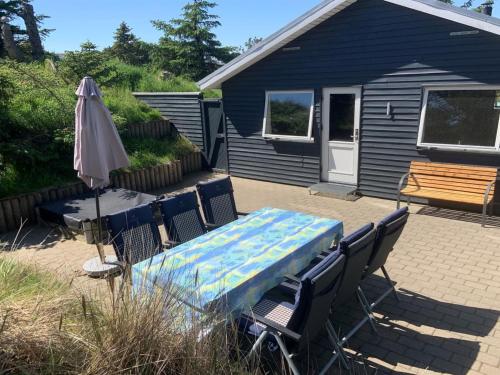 uma mesa e cadeiras e um guarda-sol num pátio em Holiday Home Gudrid - all inclusive - 500m from the sea by Interhome em Fanø