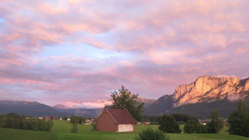 a barn in a field with mountains in the background at Hotel Drachenwand-Mondsee in Mondsee