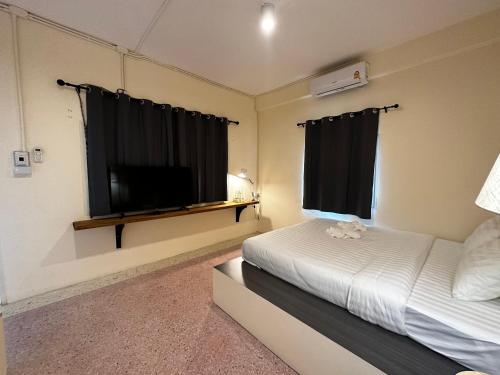 a bedroom with a bed and a flat screen tv at Norm Space Hostel NST in Nakhon Si Thammarat