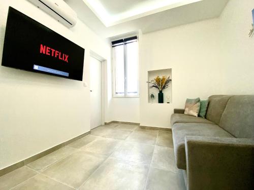 un salon avec un canapé et une télévision au mur dans l'établissement L'Esperance By SCLS Locations, à Cannes