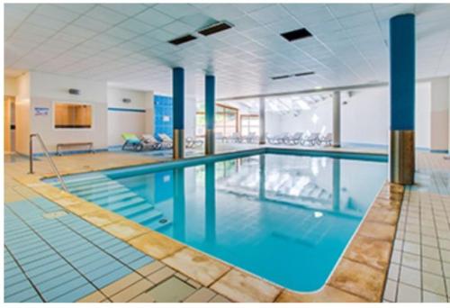 a large swimming pool with blue water in a building at Studio Croix du berger in La Féclaz