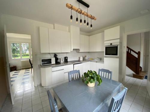 a kitchen with white cabinets and a table with chairs at Villa Marie-Lou entièrement rénovée in Neuville-sous-Montreuil