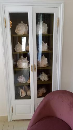 a white cabinet with glass doors filled with hats at LA LANDE in Pleyber-Christ