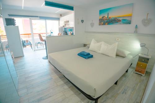 ein Schlafzimmer mit einem weißen Bett und einem blauen Kissen darauf in der Unterkunft Piso Paraíso vicino al mare in Maspalomas