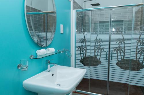 Baño azul con lavabo y espejo en kannel Apartments, en Anse Royale