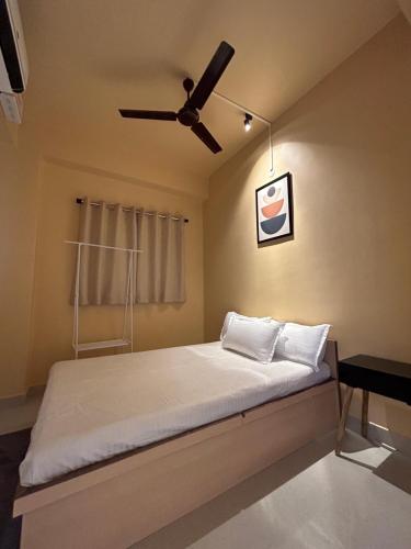 een slaapkamer met een bed en een plafondventilator bij The Serene Arc in Guwahati