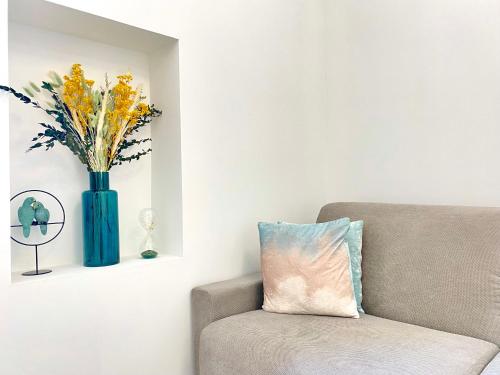 un vase bleu avec des fleurs sur un mur à côté d'un canapé dans l'établissement L'Esperance By SCLS Locations, à Cannes