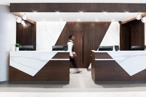a man walks past a reception desk in a lobby at Sheraton Vancouver Guildford Hotel in Surrey
