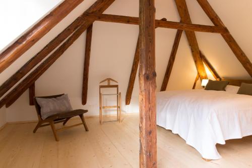 a attic bedroom with a bed and a chair at Apartement Schlaf Gut - mitten in der Wachau in Weissenkirchen in der Wachau