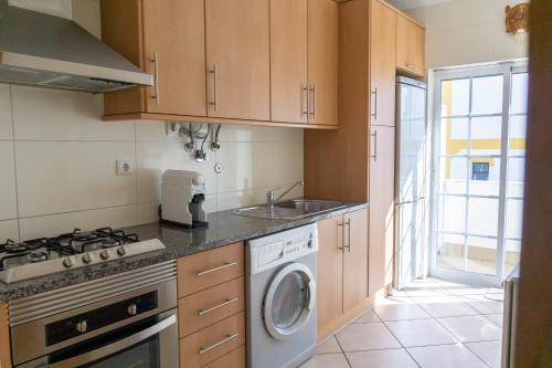 a kitchen with a sink and a washing machine at Apartamento Karibu in Carvoeiro
