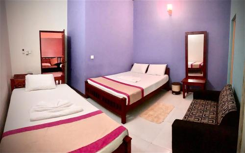 two beds in a room with purple walls at Cinnamon Tree Tourist Rest in Anuradhapura