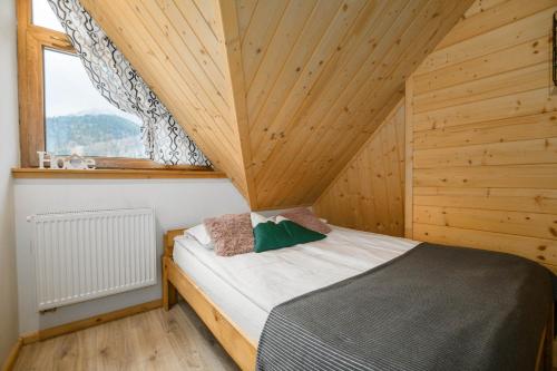 a bed in a wooden room with a window at Zakopiańska Osada Apartamenty in Zakopane