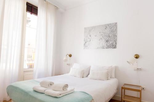 Un dormitorio blanco con una cama con toallas. en City Centre TEATRO, en Málaga