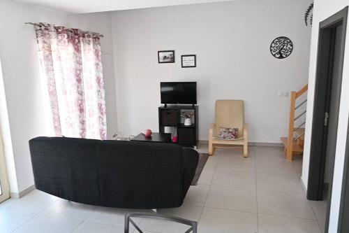 a living room with a black couch and a tv at Casinhas Escondidinho in Bajouca de Baixo