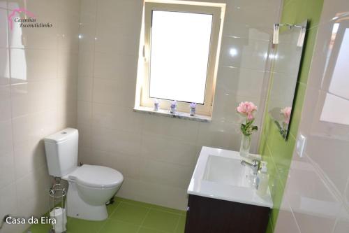 a bathroom with a toilet and a sink and a window at Casinhas Escondidinho in Bajouca de Baixo