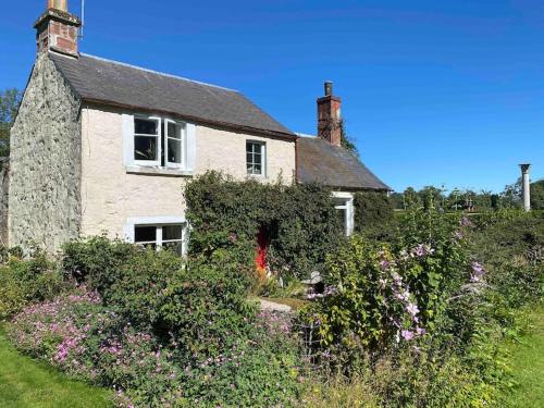 una vieja casa de piedra con flores delante en Charming, rustic & well equipped garden cottage en Alyth