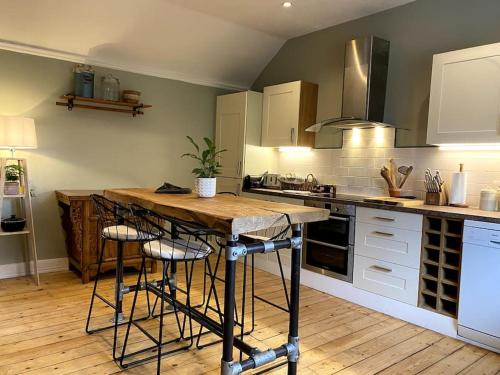 eine Küche mit einem Tisch und einigen Hockern in der Unterkunft Charming, rustic & well equipped garden cottage in Alyth