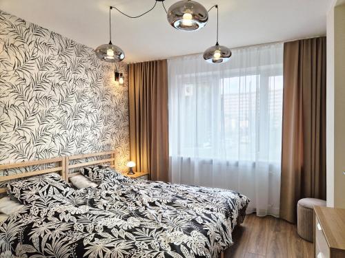 Schlafzimmer mit einem schwarzen und weißen Bett und einem Fenster in der Unterkunft City Nest Gdańsk - Komfortowy punkt na mapie Gdańska in Danzig